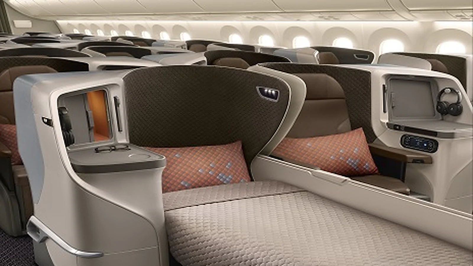 Singapore Airlines regional business class cabin, showing the seat shell, the KrisWorld screen and the batik-motif pillow